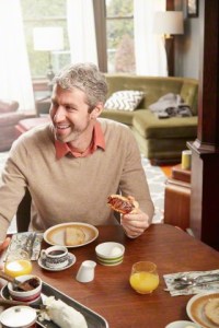 07 Jan 2015 --- Young man eating breakfast in kitchen --- Image by © Stanton j Stephens/Corbis